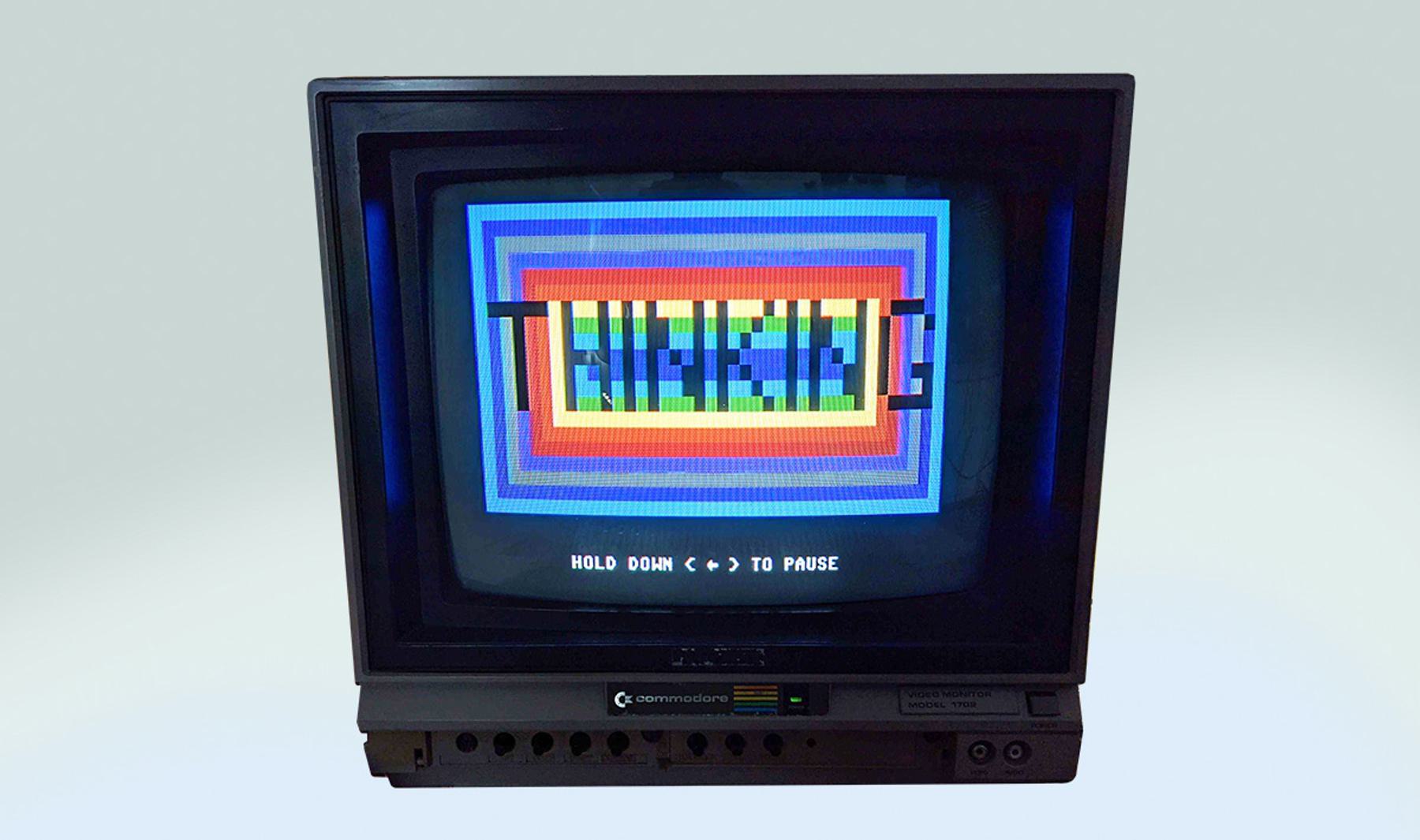 An old Commodore monitor displays a colorful, pixelated graphic with the text "THINKING" at the center.