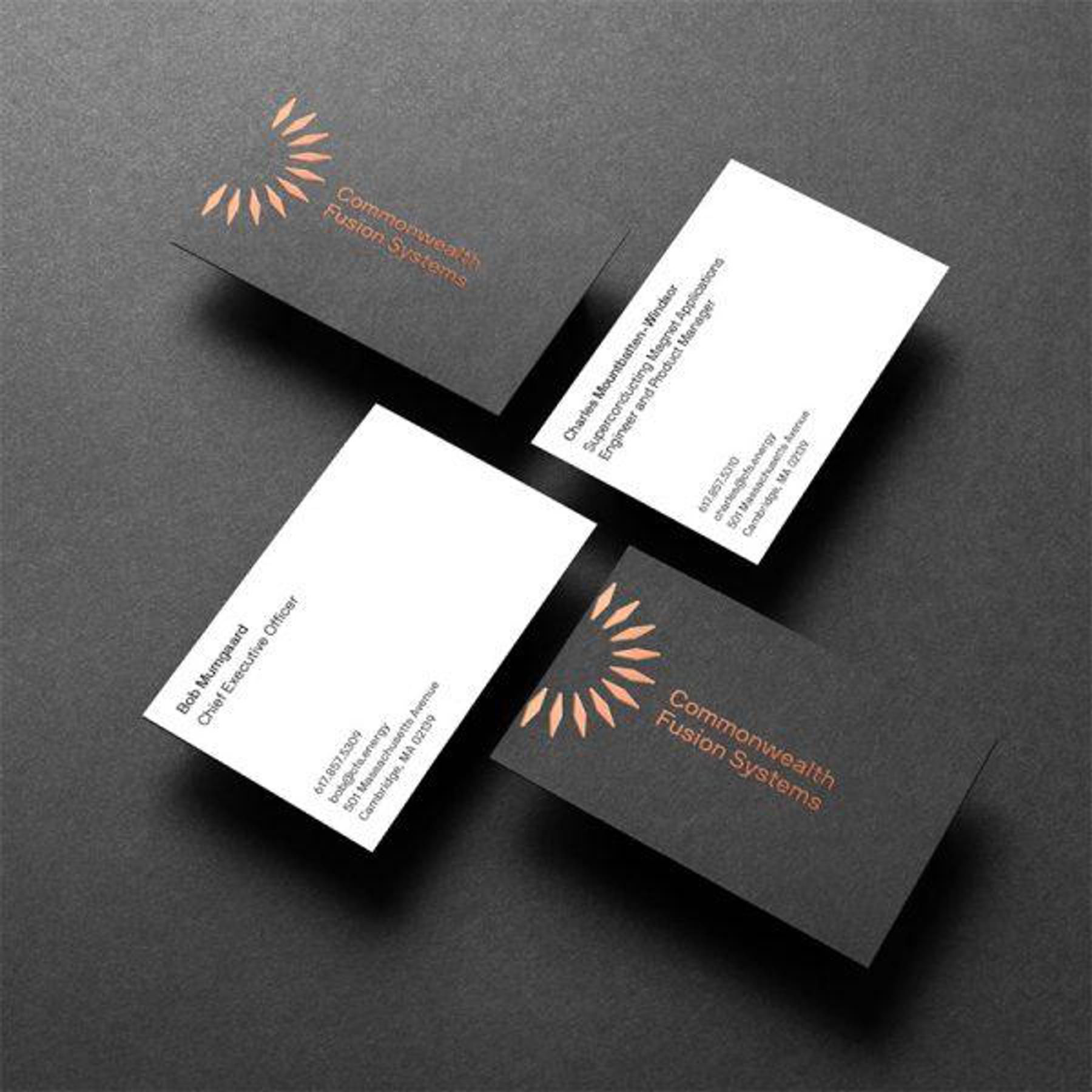Four business cards for Commonwealth Fusion Systems, two with black backgrounds and two with white. The black cards have company logo and name, while the white cards display individual names and titles with contact information.