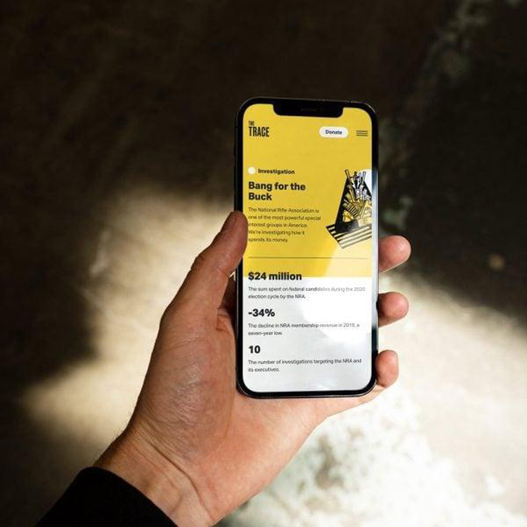 A hand holding a smartphone displaying a page from the Trade website titled "Bang for the Buck."